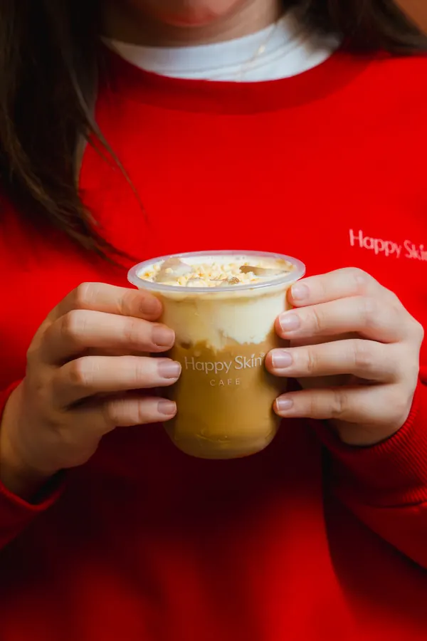 Hands holding an iced drink topped with cream