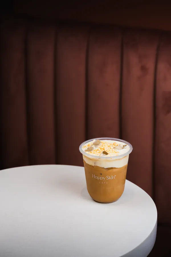 Iced coffee on a round table by a velvet banquette