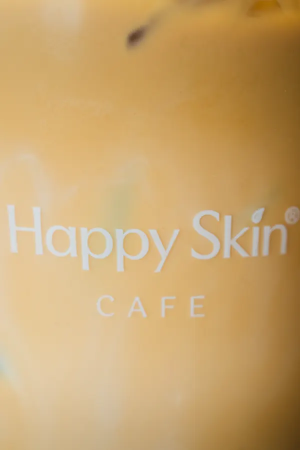 Close-up of the Happy Skin Cafe logo on a cup