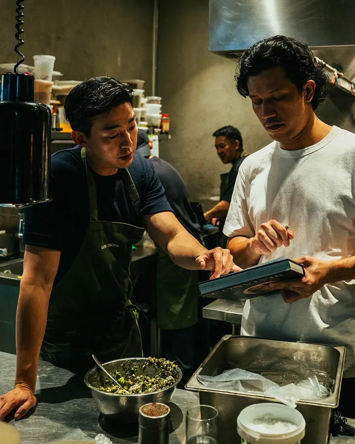 Two chefs reviewing a dish in the kitchen