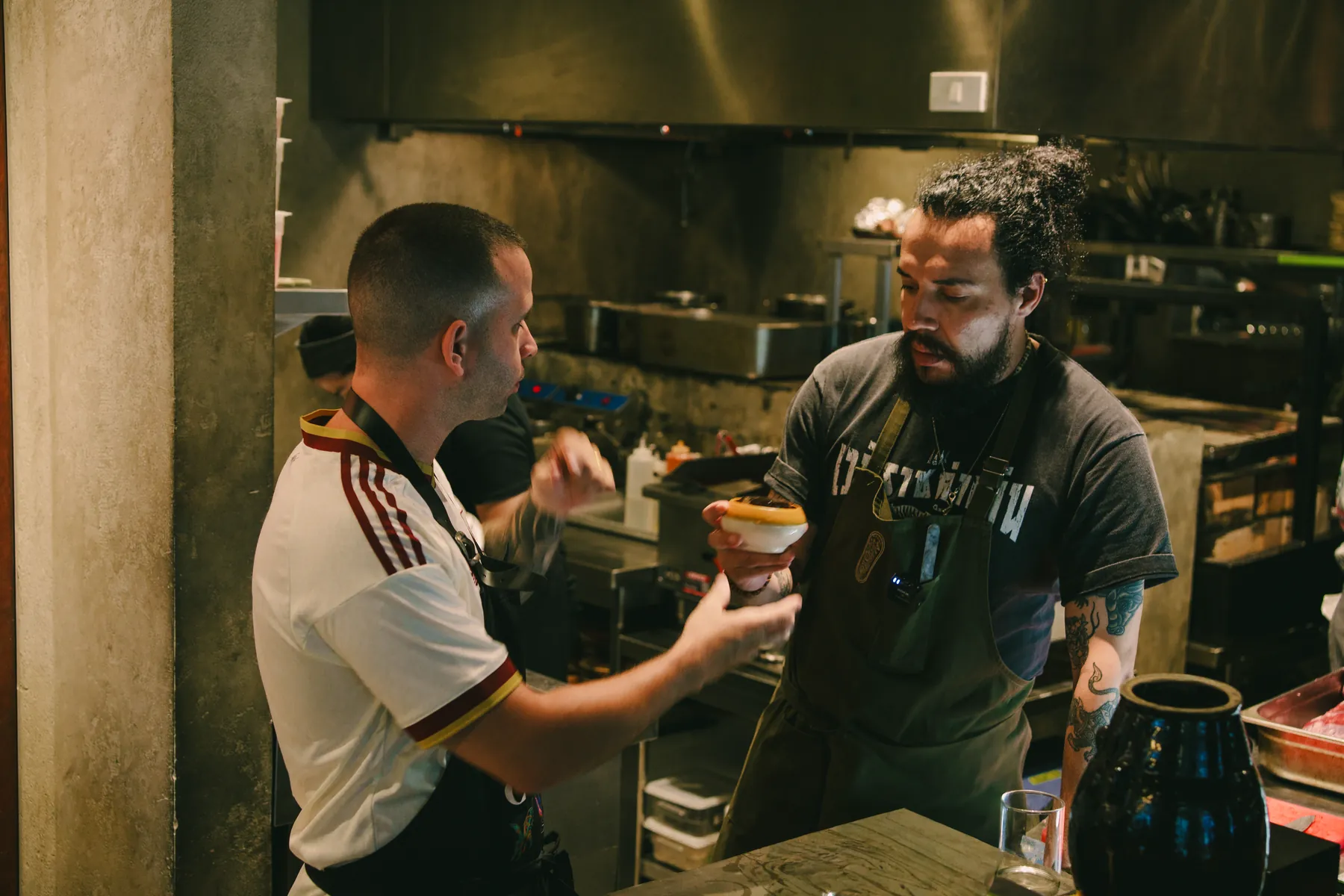 Chef handing a dish to another chef to taste in the kitchen