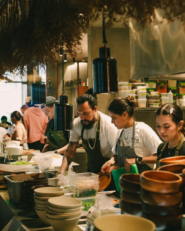 Kitchen team working under rows of hanging dried herbs