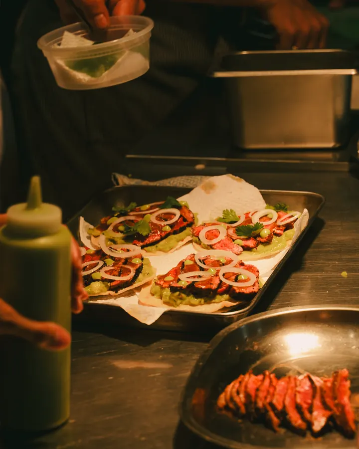 Tray of tostadas topped with sliced meat and herbs