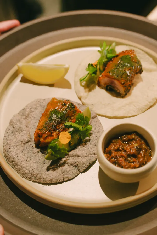 Plate of tacos with sauce and lime