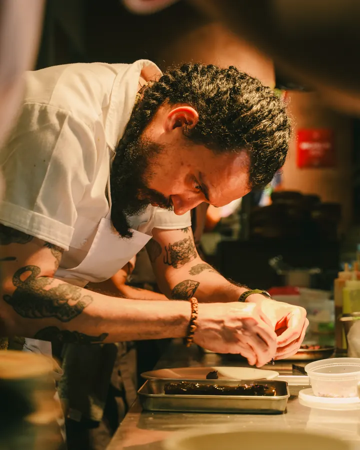 Chef with tattooed arms plating at the counter