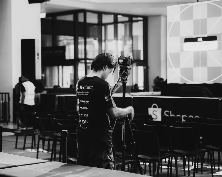 Camera operator filming the event, in black and white
