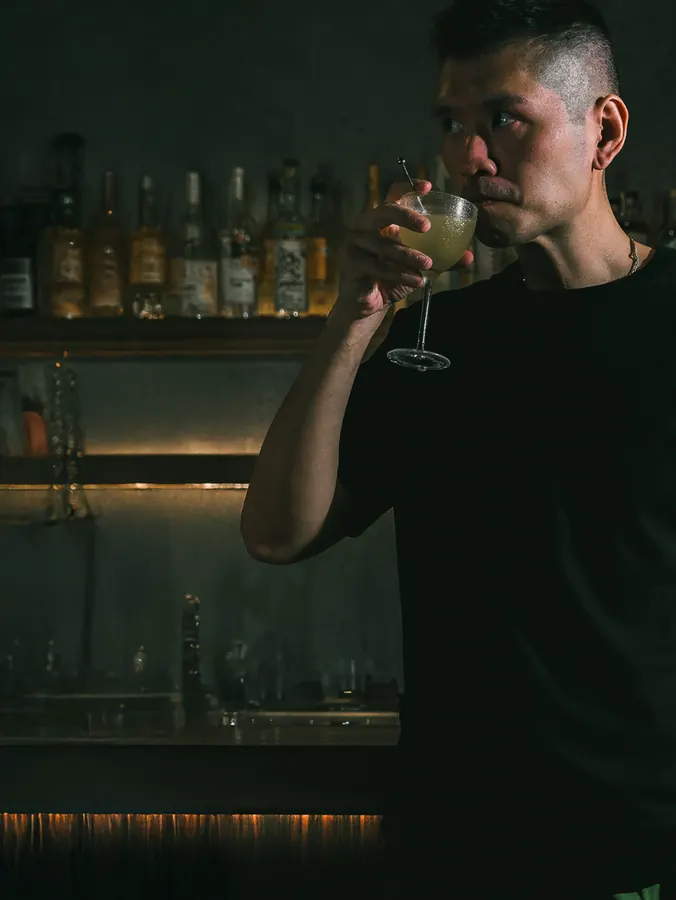 Royce Pua tasting a cocktail behind the bar