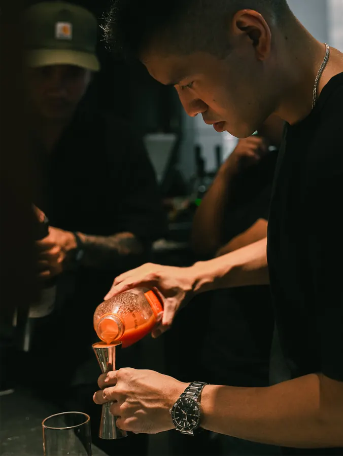 Measuring a red liqueur into a jigger